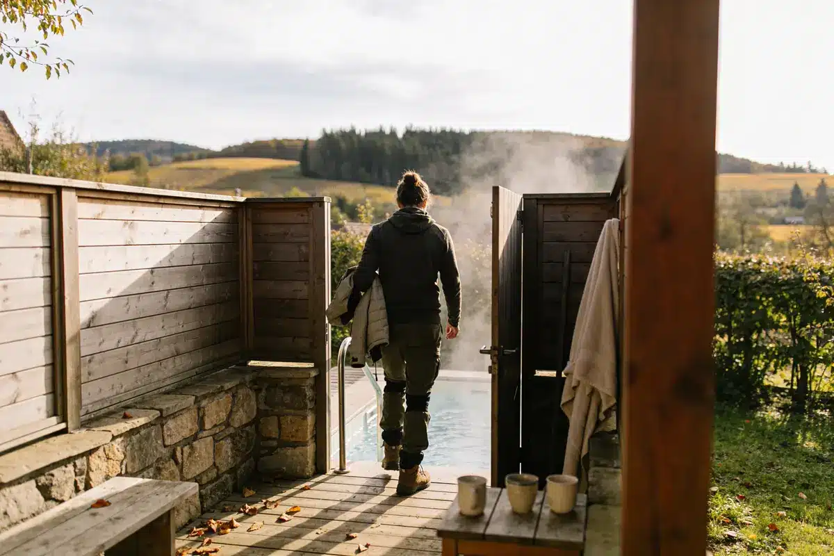 Personne avec manteau près d'une piscine extérieure par temps frais, paysage rural en arrière-plan.