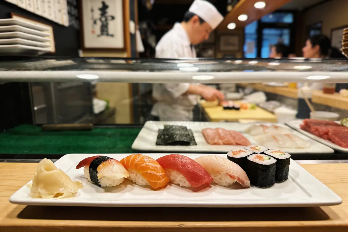 Assiette de sushis variés avec chef en arrière-plan, restaurant japonais traditionnel.